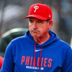 The experienced baseball manager wearing a blue jacket and a red Philadelphia Phillies cap.
