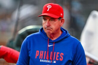 The experienced baseball manager wearing a blue jacket and a red Philadelphia Phillies cap.
