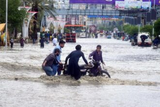 A flooded street in Afghanistan with several people helping each other recover their belongings
