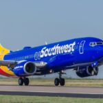 A blue airplane with a colorful tail about to take off from the runway