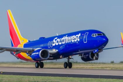 A blue airplane with a colorful tail about to take off from the runway