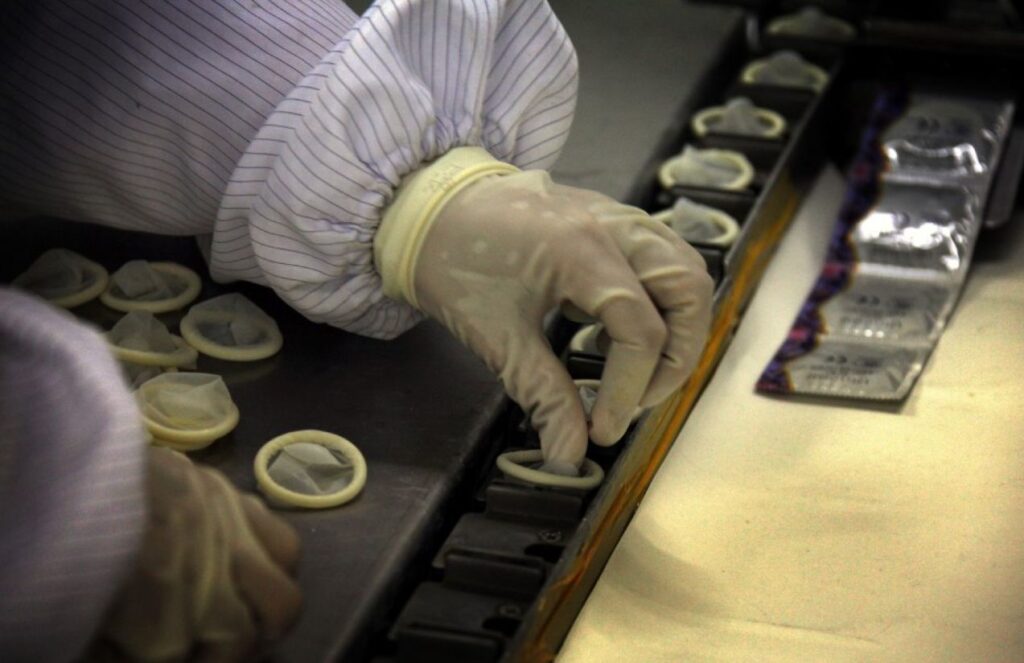 A person placing condoms in each fitting room.
