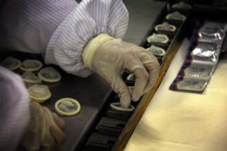 A person placing condoms in each fitting room.
