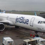 A JetBlue airplane parked waiting for all its passengers at an airport