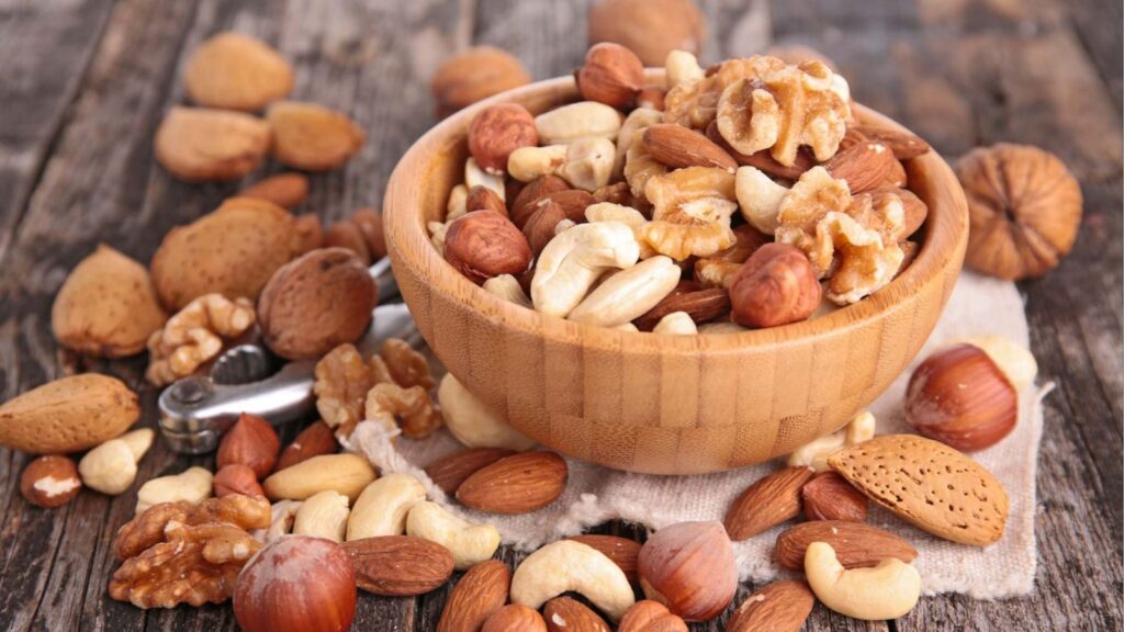 A bowl overflowing with dried fruits and nuts because it is so full.