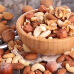 A bowl overflowing with dried fruits and nuts because it is so full.