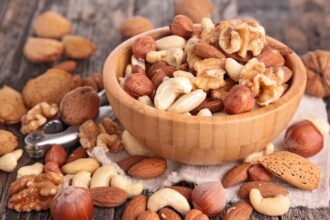 A bowl overflowing with dried fruits and nuts because it is so full.