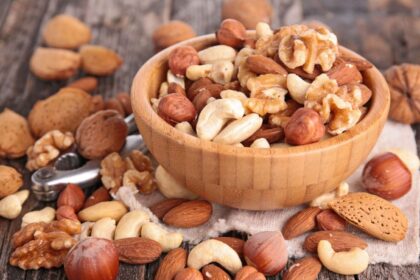 A bowl overflowing with dried fruits and nuts because it is so full.