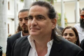 The Venezuelan businessman being escorted by several people while entering a building.
