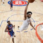 Jarrett Allen of the Cleveland Cavaliers making a dunk while two Detroit Pistons players watch him rise into the air.