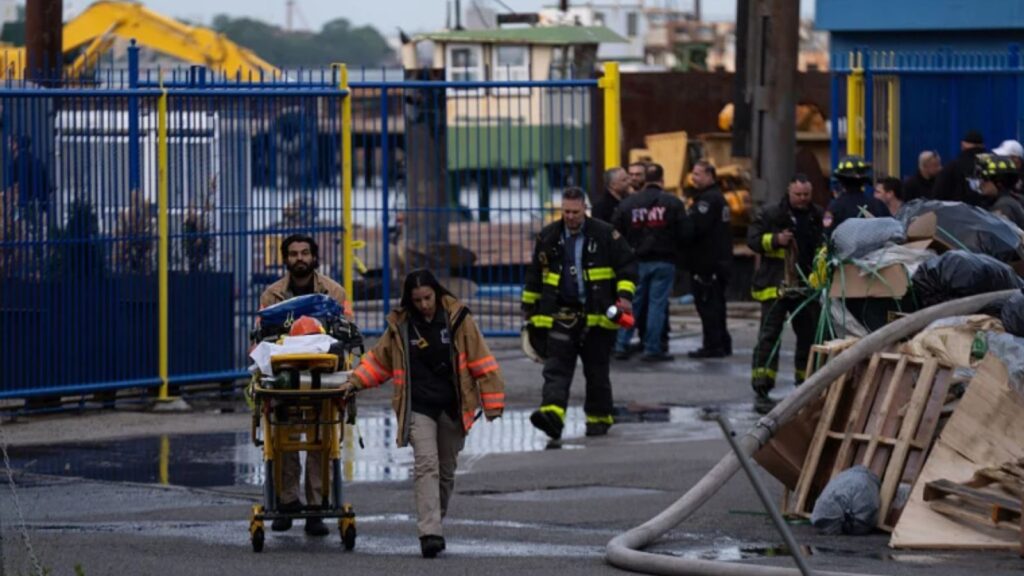Firefighters and police officers helping injured people out on stretchers.