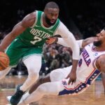 A matchup between players from both teams where one is dribbling and the other is falling to the floor.