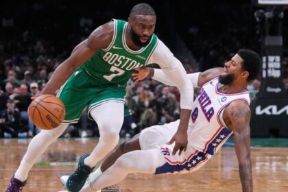 A matchup between players from both teams where one is dribbling and the other is falling to the floor.