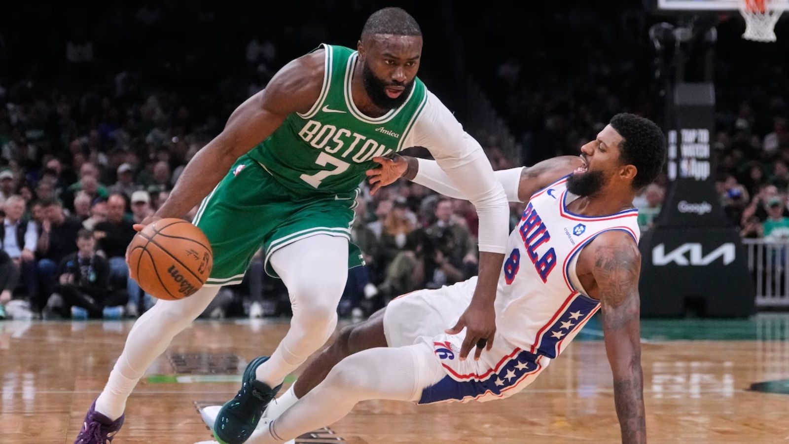 A matchup between players from both teams where one is dribbling and the other is falling to the floor.
