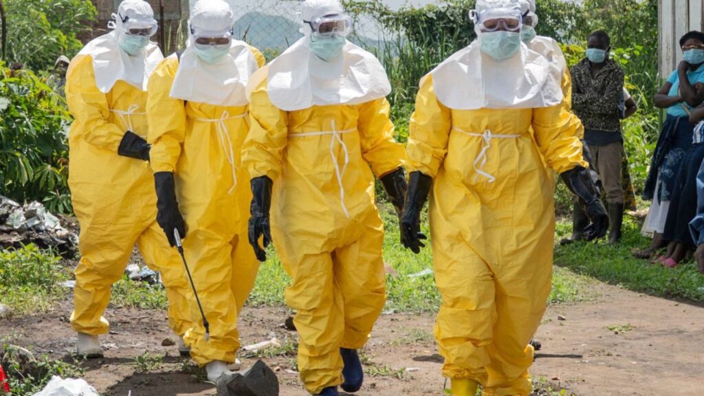 Four people wearing yellow protective suits spraying liquid on the streets to prevent the spread of Ebola.