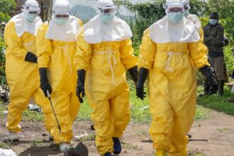Four people wearing yellow protective suits spraying liquid on the streets to prevent the spread of Ebola.
