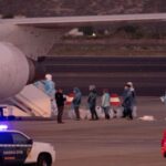 Several people wearing biohazard suits trying to board a plane linked to hantavirus.