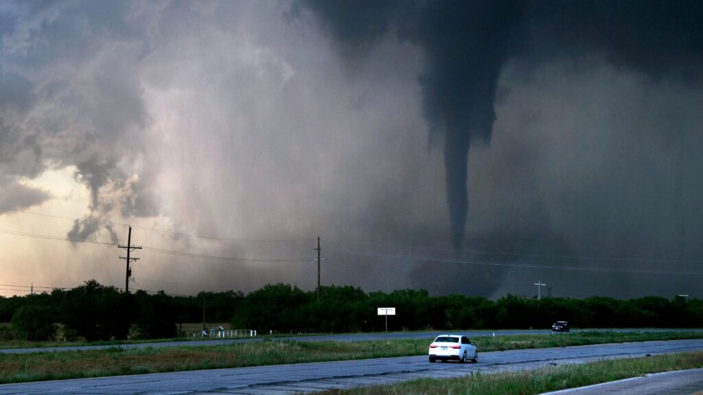 A storm turning into a small hurricane crossing a large field.