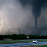 A storm turning into a small hurricane crossing a large field.