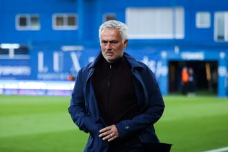 José Mourinho walking along the sideline of the pitch while his team heads toward the locker room.