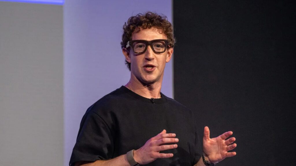 Mark Zuckerberg wearing new affordable smart glasses during a conference with a large audience.
