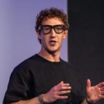 Mark Zuckerberg wearing new affordable smart glasses during a conference with a large audience.