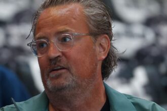 The Matthew Perry actor from Friends posing for the cameras with long hair and eye-catching glasses.