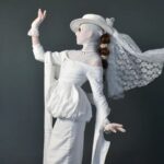 A woman wearing an eccentric white dress posing for the cameras.
