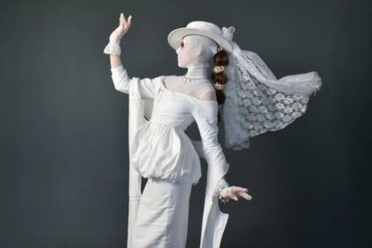 A woman wearing an eccentric white dress posing for the cameras.