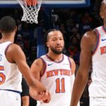 Jalen Brunson and several of his New York Knicks teammates high-fiving each other after defeating their opponent.
