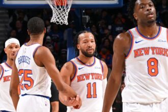 Jalen Brunson and several of his New York Knicks teammates high-fiving each other after defeating their opponent.
