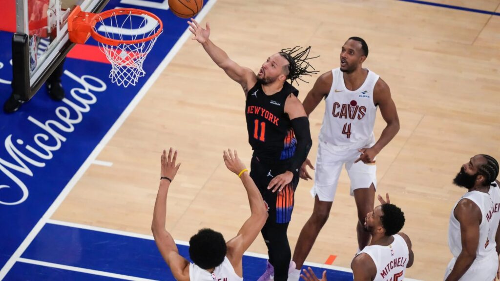 Jalen Brunson scoring from the paint while being surrounded by all the Cleveland Cavaliers players.