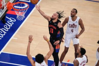 Jalen Brunson scoring from the paint while being surrounded by all the Cleveland Cavaliers players.