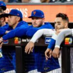 Several New York Mets players with sad expressions in the bullpen after the team’s losses.