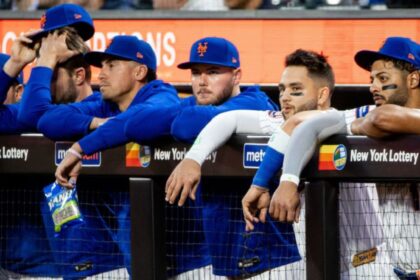 Several New York Mets players with sad expressions in the bullpen after the team’s losses.