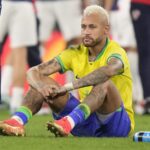 Neymar sitting on the grass of the field after finishing a match that he lost.