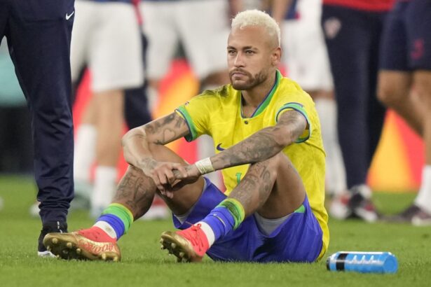 Neymar sitting on the grass of the field after finishing a match that he lost.