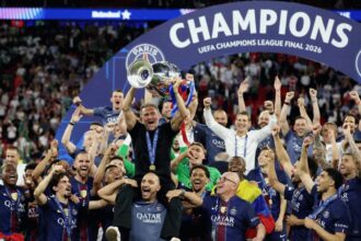 The players carrying their coach on their shoulders while he holds the Champions League trophy.