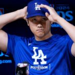 Shohei Ohtani at a press conference adjusting his cap with a slightly sad or aggressive expression.