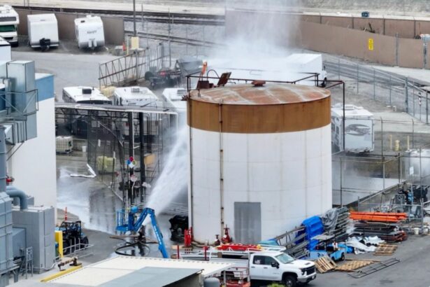A large tank filled with chemicals being sprayed with water or another liquid to prevent the gas from spreading rapidly.