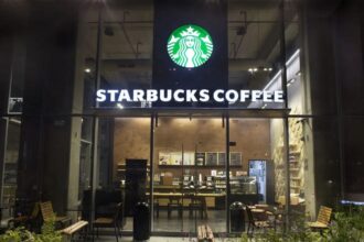 A Starbucks store viewed from the front at night with its lights and signs turned on.