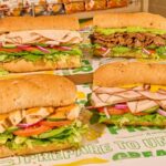 Four delicious sandwiches placed on a green table.