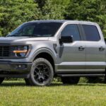A hybrid Ford pickup truck parked on grass for a photoshoot.