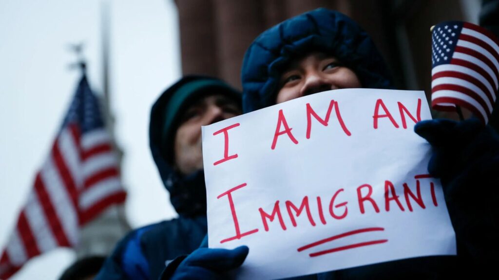 United States will impose fines of up to $18,000 on migrants with deportation orders A person with their face covered holding a sign that says “I’m an immigrant.”