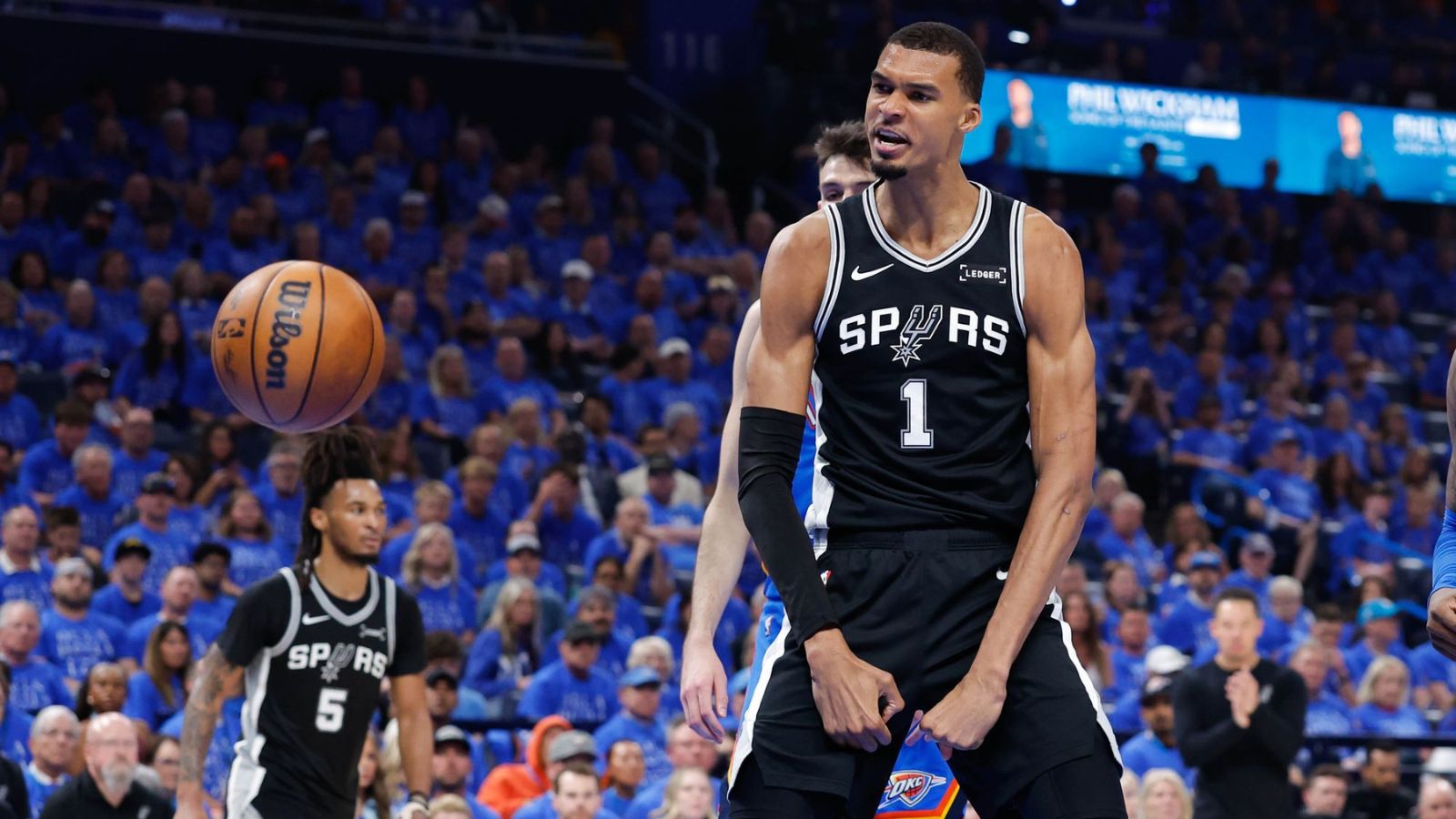 The NBA player standing over seven feet tall celebrating a basket in front of the Oklahoma City Thunder fans.