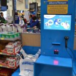 A blue and yellow self-checkout machine in the middle of a store.