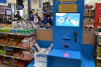 A blue and yellow self-checkout machine in the middle of a store.