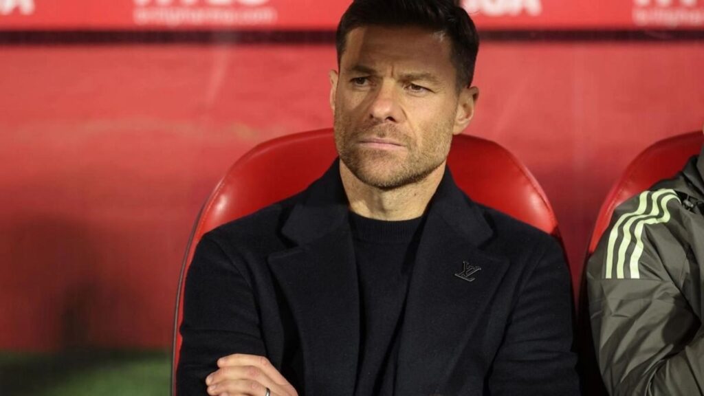 The former player and now Spanish coach sitting on a stadium bench while watching his team play.