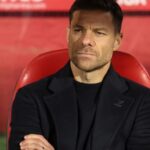 The former player and now Spanish coach sitting on a stadium bench while watching his team play.