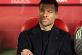 The former player and now Spanish coach sitting on a stadium bench while watching his team play.